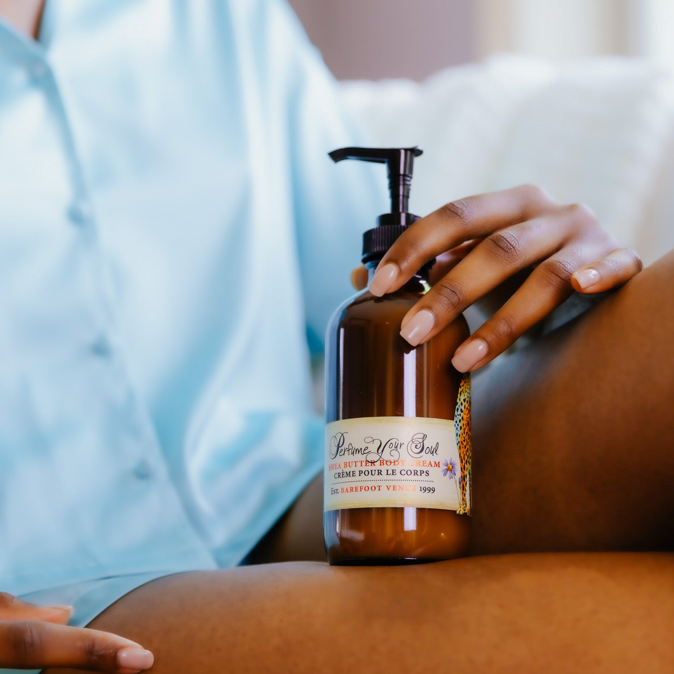 Person holding a brown bottle with a pump on a blurred background