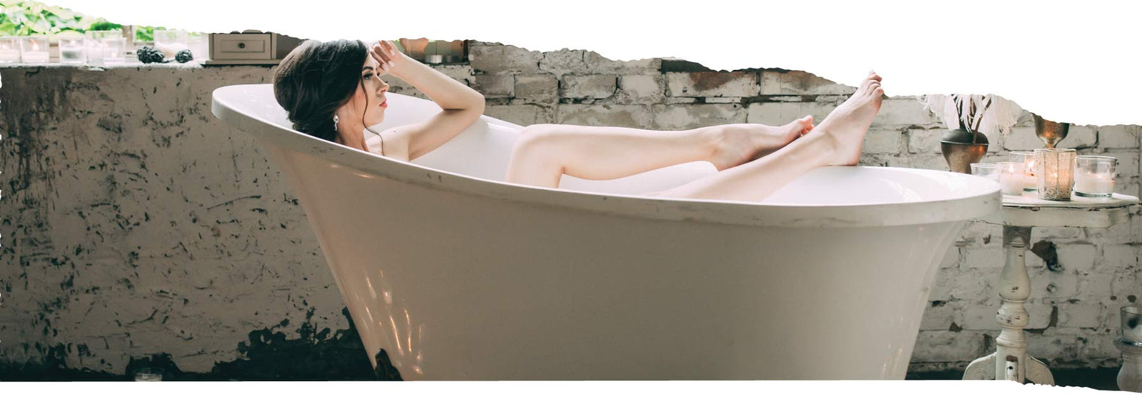 Woman relaxing in a white bathtub with her legs resting on the edge