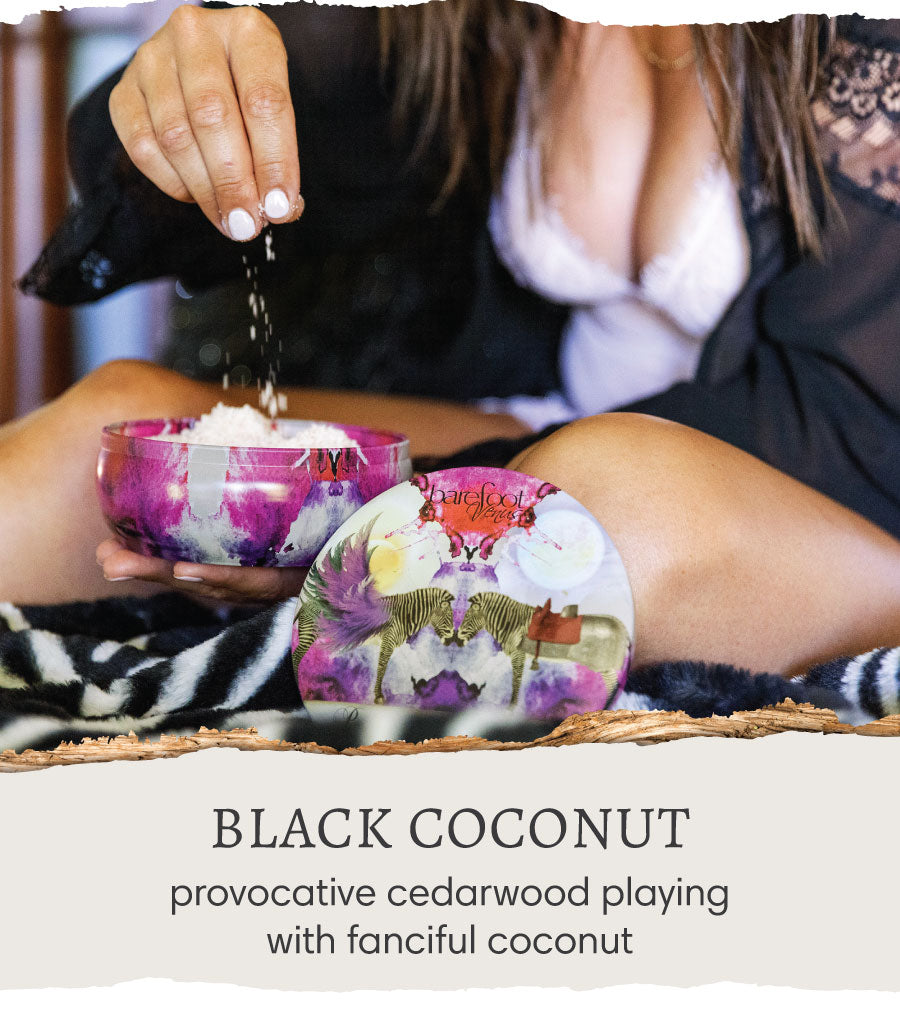 A woman holding Barefoot Venus Black Coconut salt bath. Text reads "Black Coconut - provocative cedarwood playing with fanciful coconut".