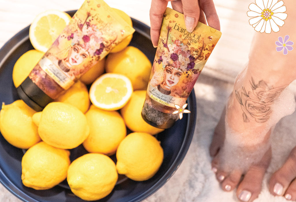 Person holding a tube of Barefoot Venus Lemon Freckle shower gel over a tub of lemons