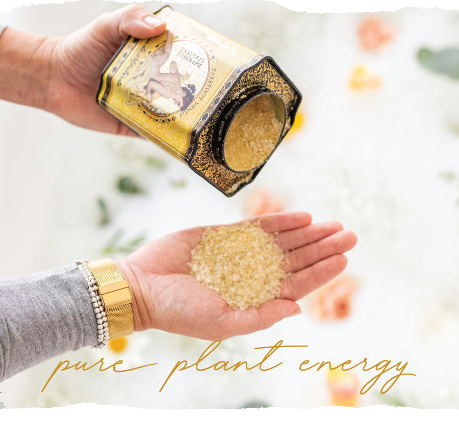 Person pouring a container of Barefoot Venus Mustard Bath soak into their hand above a bath tub with a blurred background